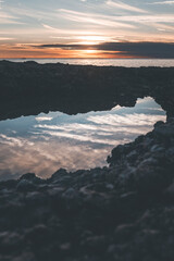 pale sunset from the town of porec in croatia, with reflections on the water and rocks foreground