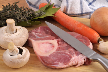 Osso bucco de veau cru avec un couteau et des ingrédients en gros plan