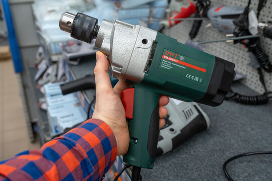 DWT brand electric drills are sold in the power tool store. A customer selects an electric drill. Electric drill in hand. Minsk, Belarus - june 26, 2025