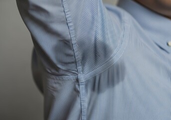 Cropped shot of a man’s blue shirt with visible underarm sweat stains, highlighting the effects of heat or stress – personal care and comfort concept