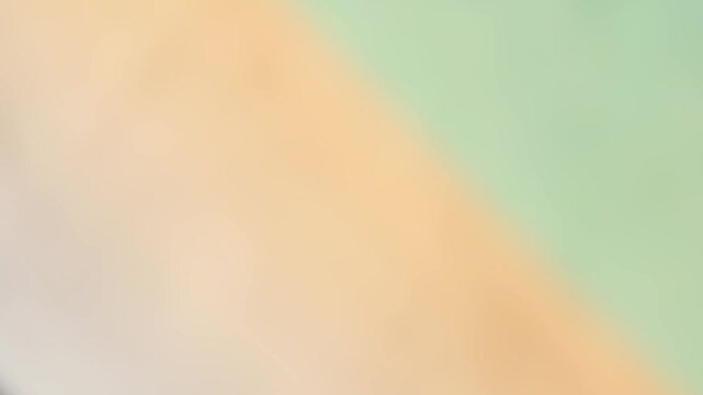 Abstract background featuring a soft, blurred split of cool mint green and warm peach tones, creating a gentle, harmonious color transition 4k background video