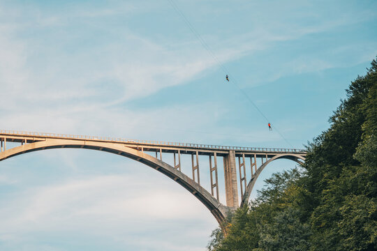 Tourists ziplining over the historic Durdevica bridge and Tara canyon, experiencing adventure, thrill, and extreme sports in nature