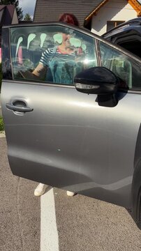 Woman cleaning car window in sunny day