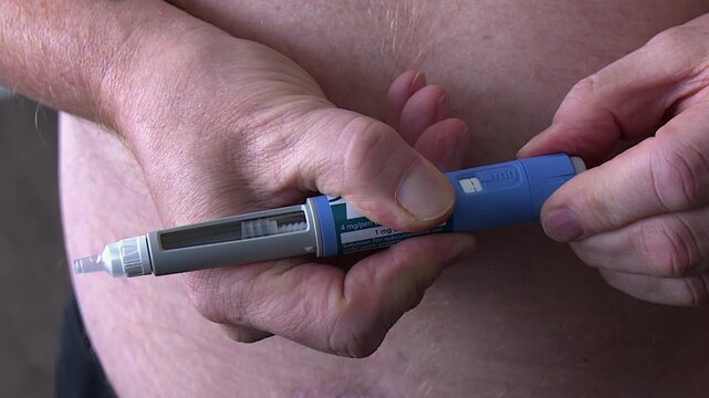 Man turns dosage knob on medical injection pen to adjust drug dose