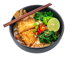 A close-up of a noodle bowl with crispy fried topping, greens, chili peppers, and lime, viewed from above on black