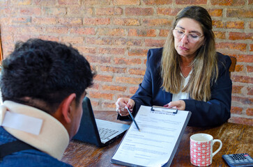 Mature adult female lawyer assist a injured man with legal problem. Lawyer showing document. Compensation for work or car accident. Legal concept. Social Worker.