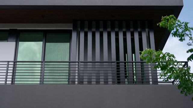 Upper part of modern building. On the left side, there are large glass windows with green tinted glass. On the right side, there are black vertical slats