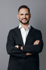 A confident business professional man stands with arms crossed against a solid gray background, projecting focus, confidence, and poised leadership in a modern corporate setting for branding and