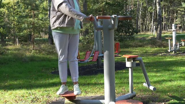 Woman training on outdoor stepper in sunny park. Concept of fitness, strength, motivation and healthy lifestyle. Ideal for wellness, sport and active life visuals.