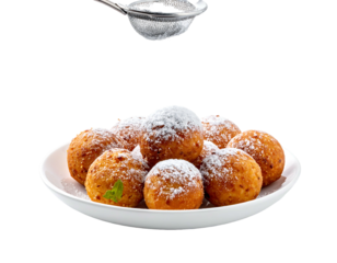 A white plate of fried dough balls covered with powdered sugar, sifting down, on a dark background