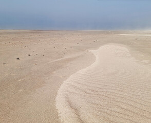 Obraz premium Misty shoreline with gentle waves, sand textures and a tranquil coastal atmosphere.