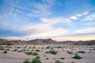 Wide angle view of the dramatic desert mountains and sparse vegetation under a wispy blue sky on the long road trip from Luxor to the Red Sea resort of Hurghada Egypt.