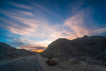 Spring dusk in Hurghada, Egypt, reveals dramatic clouds, rocky hills, and roadside power towers during a scenic bus ride.