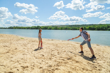 Father and daughter having fun on the beach during summer vacation playing beach tennis