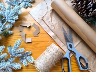 Christmas gift wrapping in paper and a recycling symbol made from kraft paper. christmas decoration on wooden background