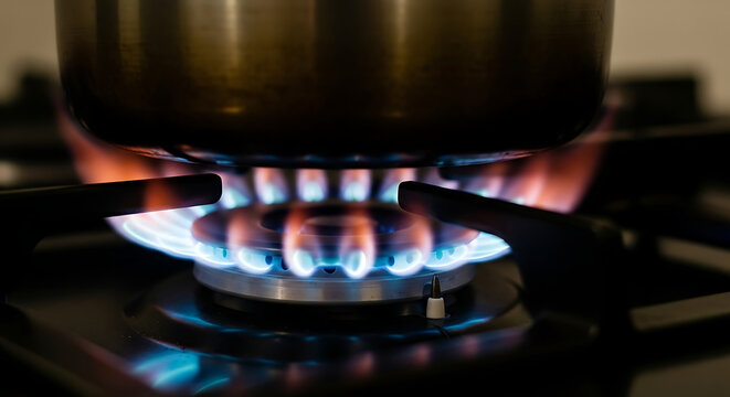 Close-up of a gas stove burner with blue and orange flames heating a pot