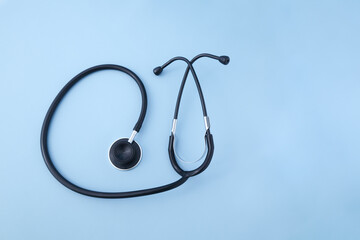 A black stethoscope on an isolated blue background