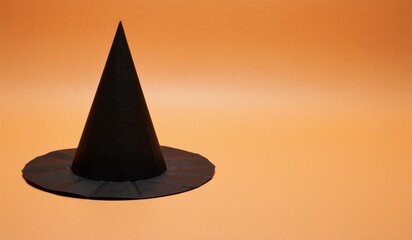 Fototapeta premium Black witch hat resting on a warm orange background in festive ambiance Generative AI