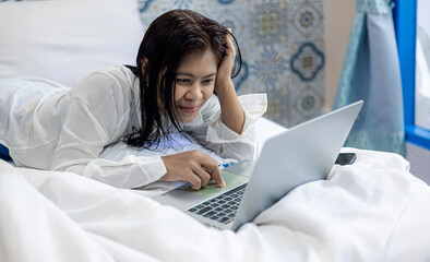 Woman relaxing on bed using laptop, work from home and online communication lifestyle