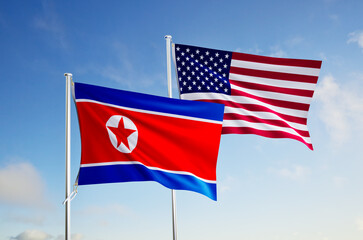 flags of united states of america and north korea over blue sky background.