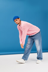 Fashionable young man showcases style against a vibrant blue background with modern flair