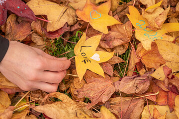 Hand holding yellow maple leaf with heart and “Love” written on it – autumn background top view