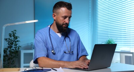 Doctor working on laptop at table in clinic during night shift