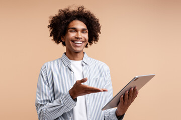 Young cheerful Black man presenting tablet technology