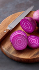 Purple radish slices on wooden cutting board with kitchen knife, fresh vegetable food