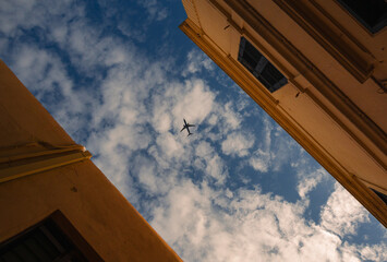 Plane in the sky. View between houses. Holiday concept