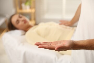 Reiki master showing his hand while healing patient's aura during therapy indoors, closeup