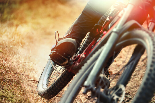 Mountain biker cornering fast on dusty downhill trail. Intense action shot with motion blur, dynamic movement and sunlight. Gravity and speed concept.