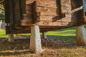 Rustic old wooden building or granary resting on rough stone pillars, lifting the structure from...
