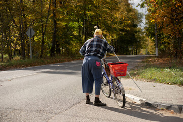 Old man on a bicycle. Senior man on autumn day outdoors. A man with a bicycle is standing by the...