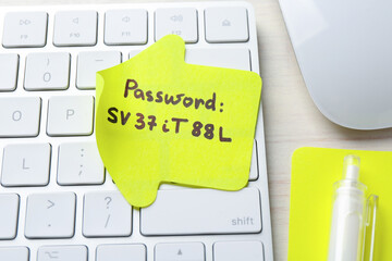 Paper note with password and keyboard on table, closeup