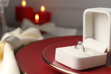 Romantic place setting. Box with engagement ring, plates and napkin on table, closeup