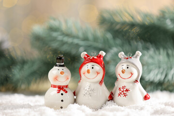 Cute decorative snowmen on artificial snow against blurred background, closeup