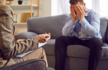 Distressed frustrated upset adult man sitting on the couch with head in his hands. Counseling...