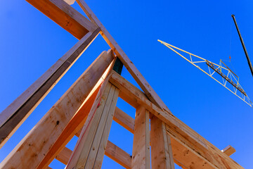 Workers erect wooden structures at construction site under blue sky, building process.