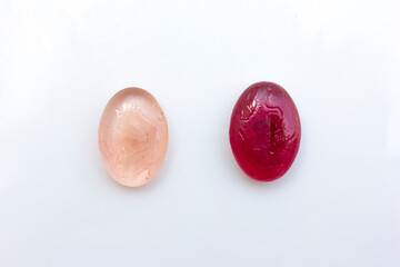 Two sweet delicious glistening red candies, isolated on white background