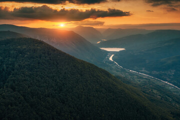 Drina river winding through a green mountain valley in Tara natural park at golden hour, dramatic...