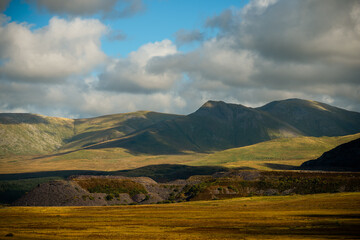 Sunlit peaks and rolling hills under dramatic clouds in Snowdonia, Wales