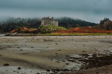 A dramatic and atmospheric photograph of the ruined medieval Castle Tioram (pronounced "Cheerum"), the former stronghold of the Clanranald branch of the MacDonalds - in Loch Moidart