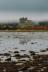 A dramatic and atmospheric photograph of the ruined medieval Castle Tioram (pronounced "Cheerum"), the former stronghold of the Clanranald branch of the MacDonalds - in Loch Moidart