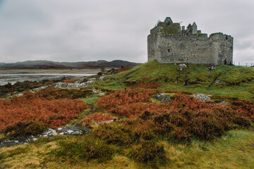 A dramatic and atmospheric photograph of the ruined medieval Castle Tioram (pronounced "Cheerum"), the former stronghold of the Clanranald branch of the MacDonalds - in Loch Moidart