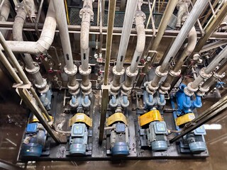Top-down view of a row of blue and yellow centrifugal pumps and electric motors connected to an...