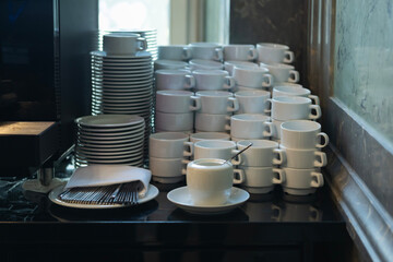 Cups and saucers neatly arranged on a table in a modern cafe setting during a busy morning service