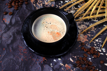 Coffee with foam in a black ceramic cup on dark background