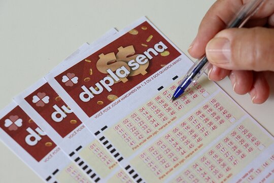Jogo da Loteria Dupla Sena (Dupla Sena Lottery Game). Person filling out a Dupla Sena lottery ticket. Brazilian lottery concept.