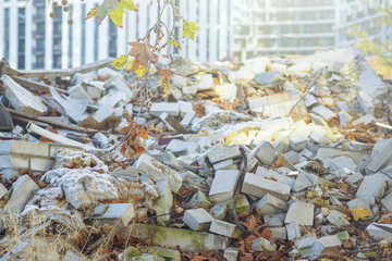 View of demolished building fragments illuminated by rays of sun. Concepts of construction waste challenge, demolition site ecology, circular economy opportunity, and building material recovery. 